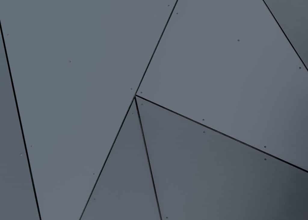 Grå væg med geometrisk mønster, anvendt som baggrundsbillede i relation til Dansk Erhvervsoptik og visuel identitet for erhvervsoptik løsninger