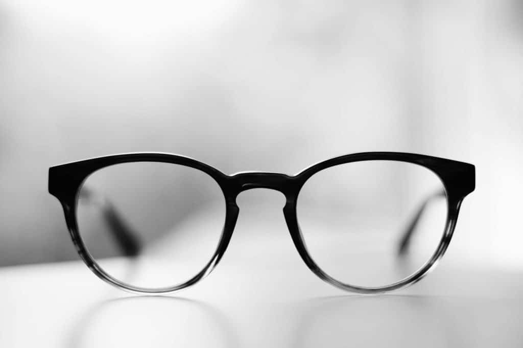 Sort skærmbriller i tæt udsnit på lys baggrund, der fremhæver stellets form og glas.